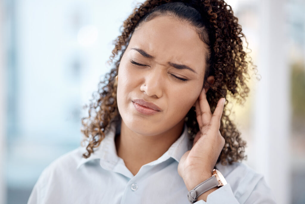 "Persona tocándose el oído con expresión de preocupación debido al tinnitus."